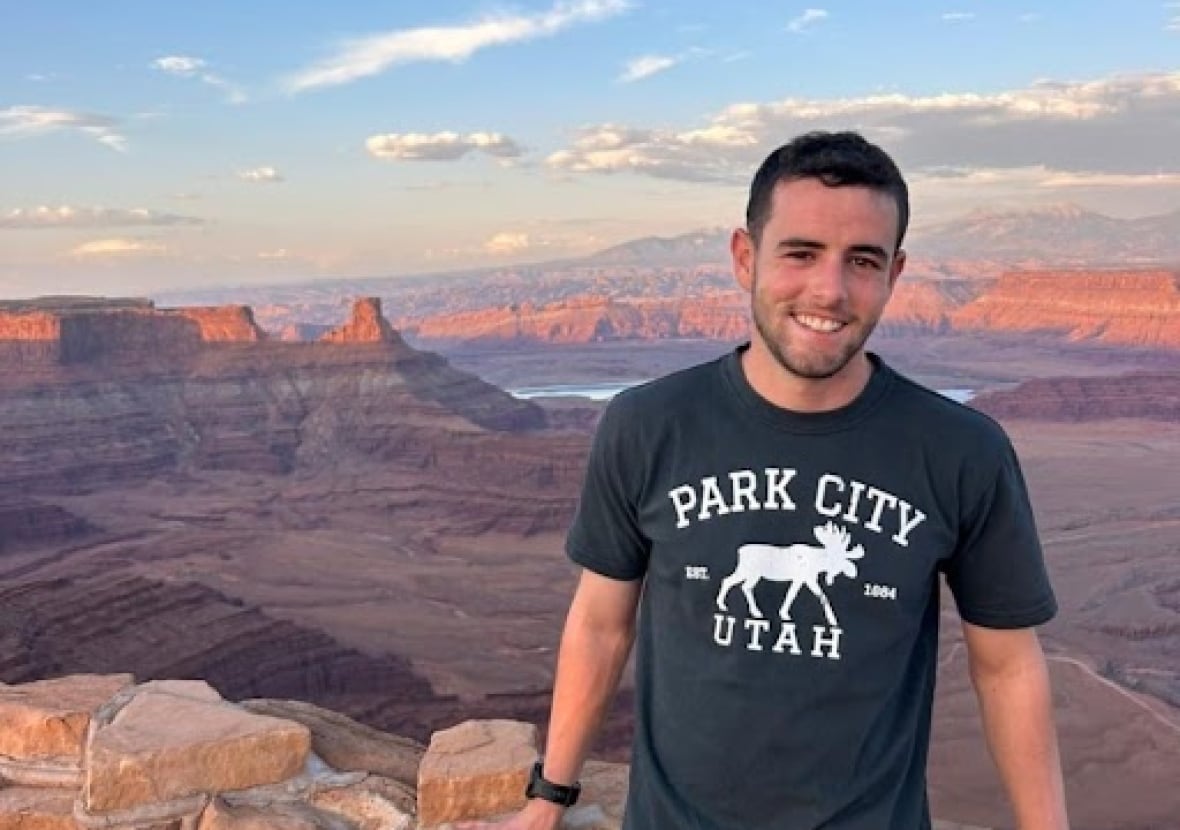 A man stands in a black shirt smiling in front of Grand Canyon.