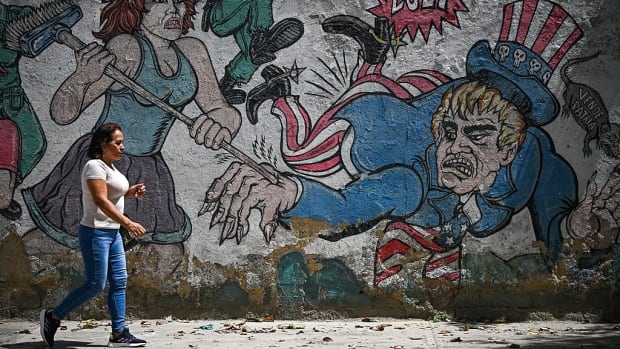 A woman walks in front of a mural depicting US Uncle Sam in Caracas on September 1, 2025. Venezuela's President Nicolas Maduro claimed on September 1, 2025, that eight US military vessels "with 1,200 missiles" were targeting his country, denouncing an "absolutely criminal, bloody threat." A woman walking past a mural depicting the U.S. Uncle Sam character, as seen in Caracas, Venezuela, in September 2025.