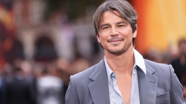 A man in a suit with an open shirt smiles for the camera.