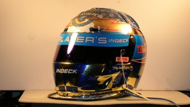 A blue and orange racing helmet with a black visor sits on display.