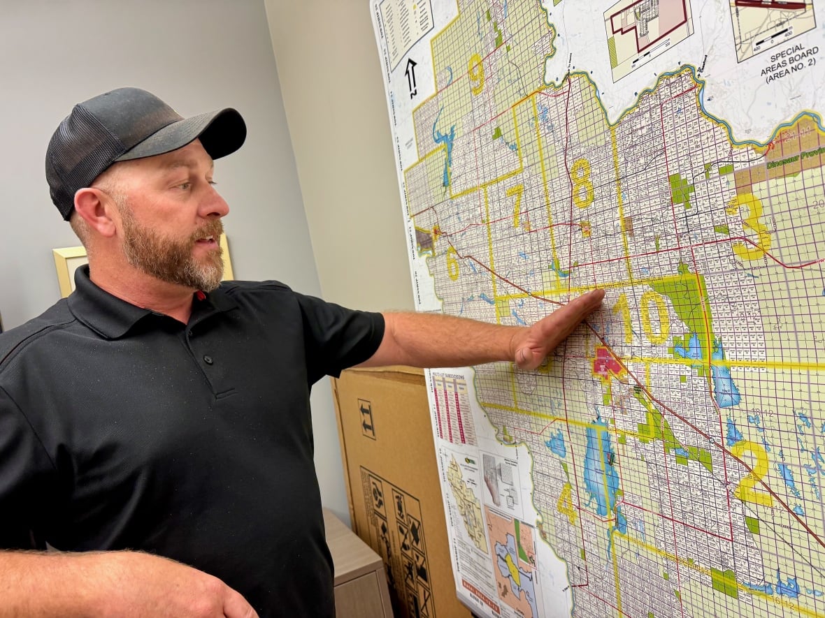 A man points to a Newell Alberta County map, near Brooks, to illustrate the path of hail storm.