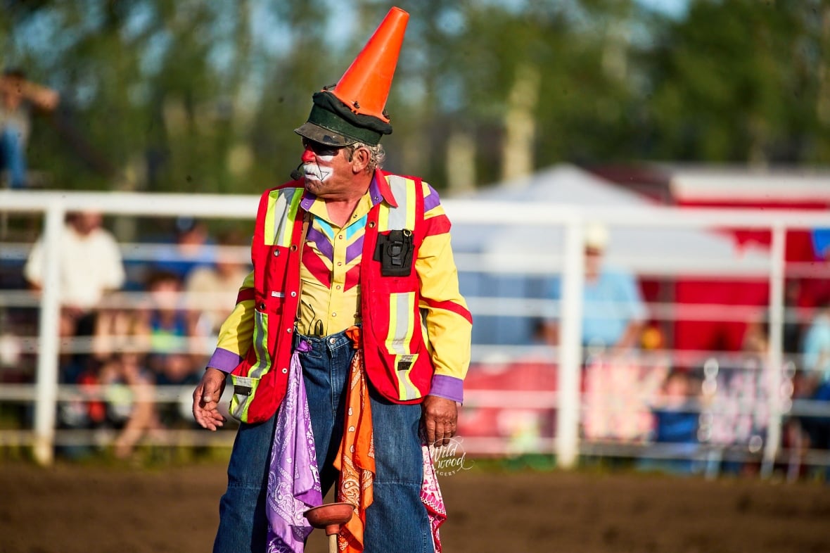 A clown with an orange cone on his head.