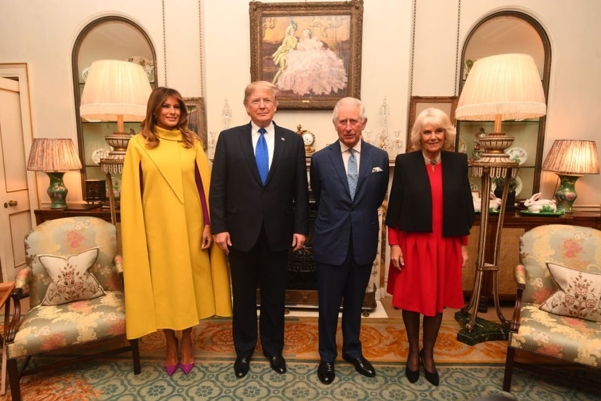 Four people stand in a formal living room.