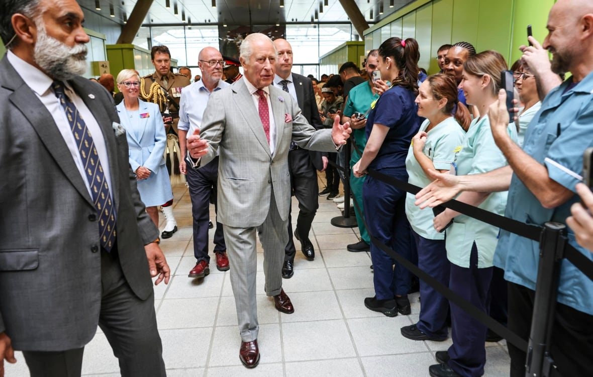 A person holds out their arms as they walk between two rows of people.
