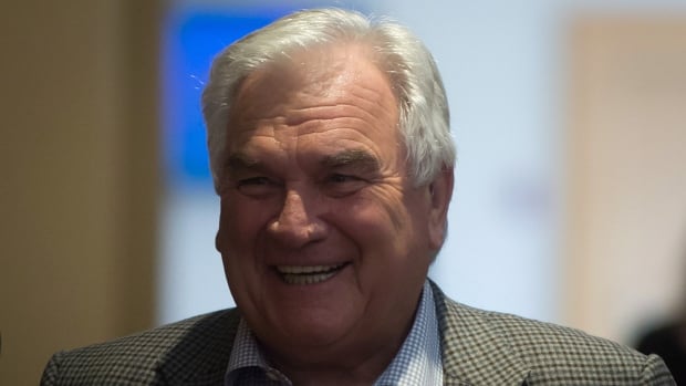 A man with short white hair smiles.