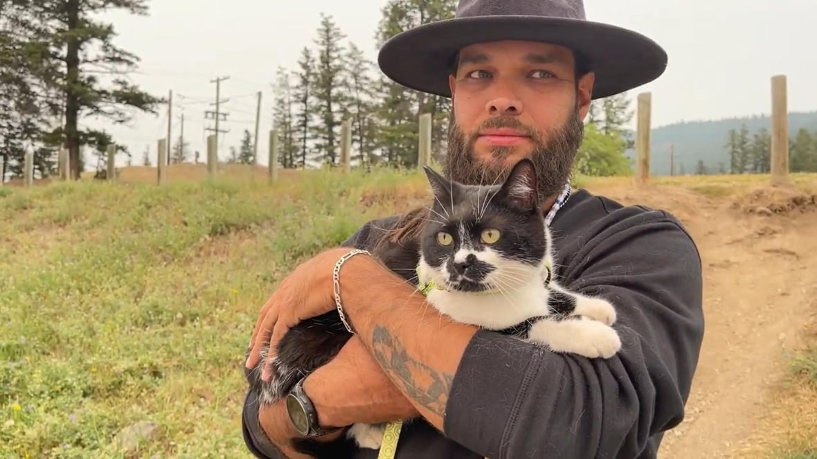 A man in a hat holds a cat