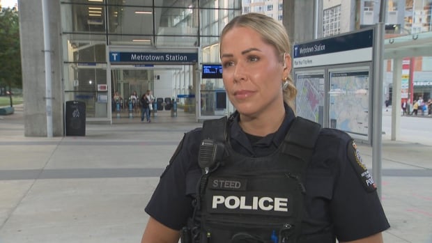 A police officer with blond hair is seen outside a transit station.