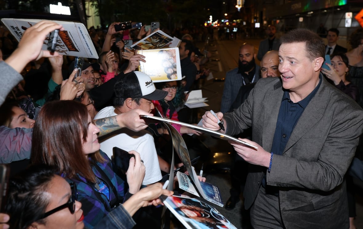 A man signs papers for excited fans