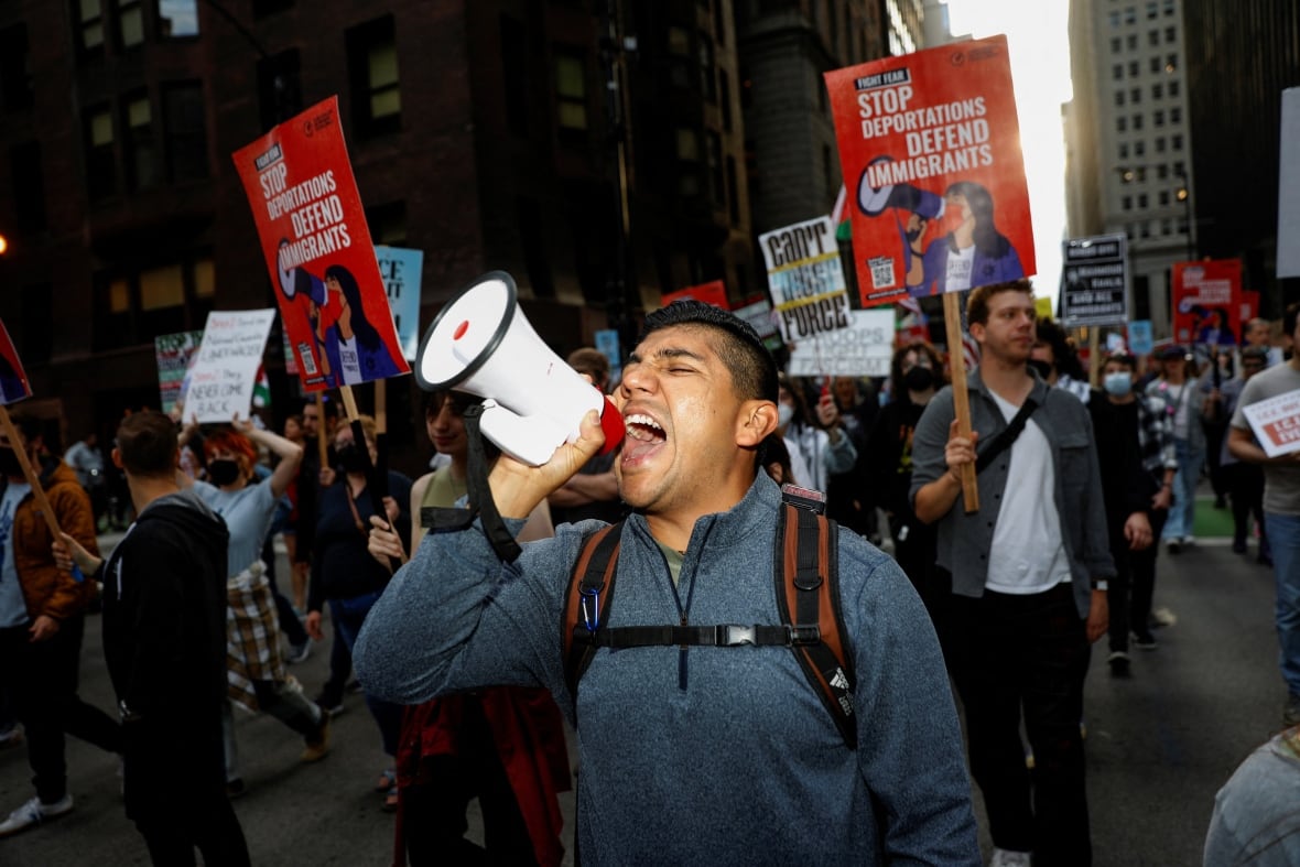 A man was seen screaming in amplifiers while many other people can be seen behind him carrying signs