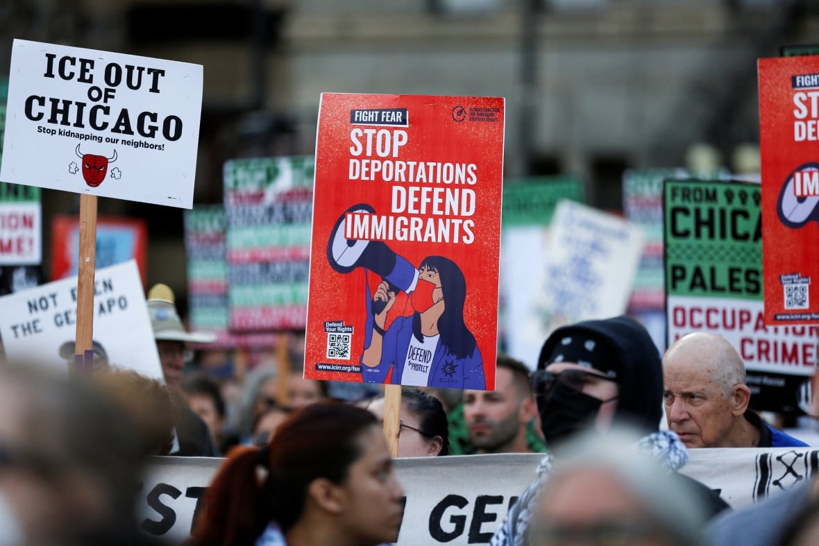 A crowd of people seen holding signs and codes, with red in the middle of the photography photographic photographer and expulsion names protect immigrants