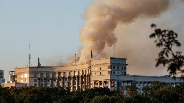 Smoke rises over a large curved building.