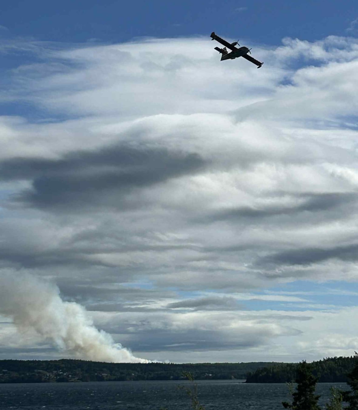 Small plane in sky flying over smoke cloud