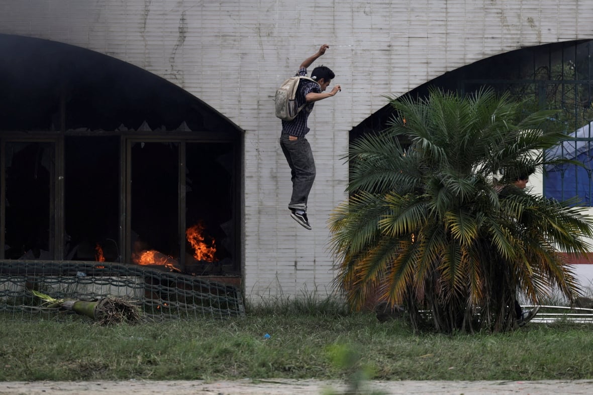 A young man wearing a backpack is shown in the air, appears at the end of jump from a higher place. 