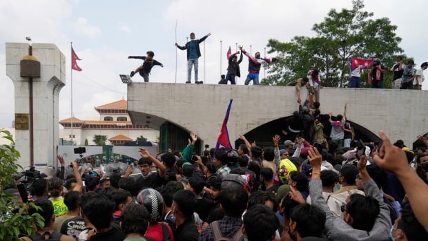 Dozens of people are shown in a crowd in an apparent demonstration, with some other people standing on top of a building overhead.