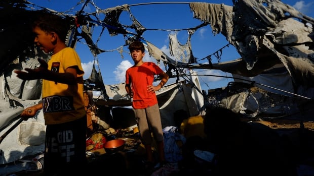 Children look at the damage at a tent site in Gaza.