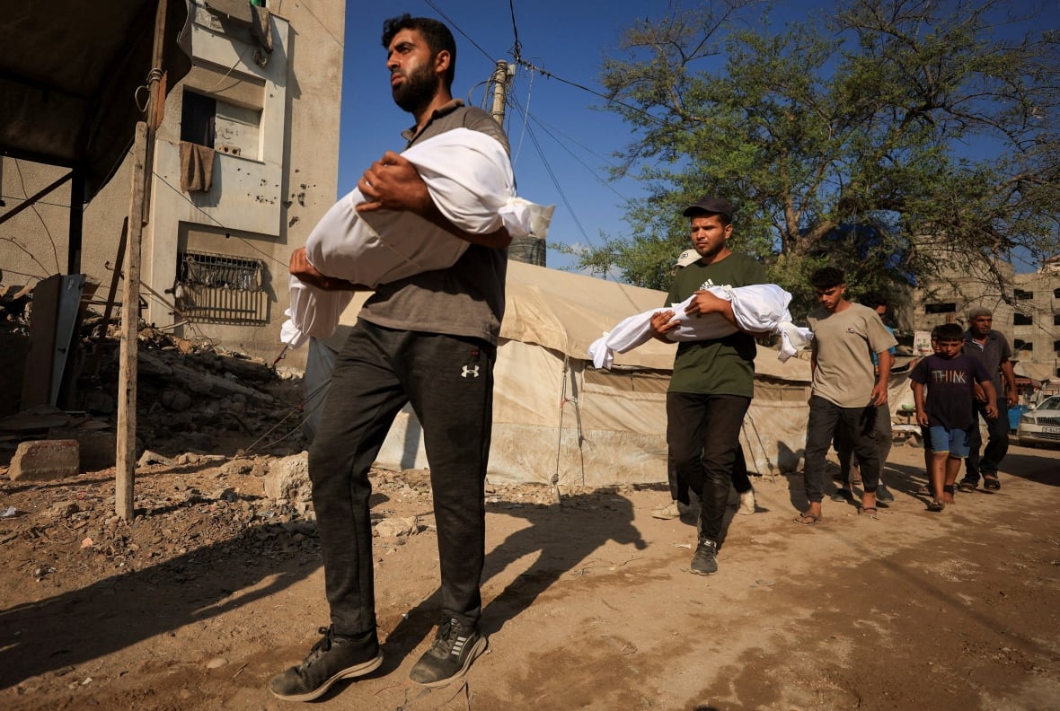 Men carry the bodies of young children who were killed in an air strike.