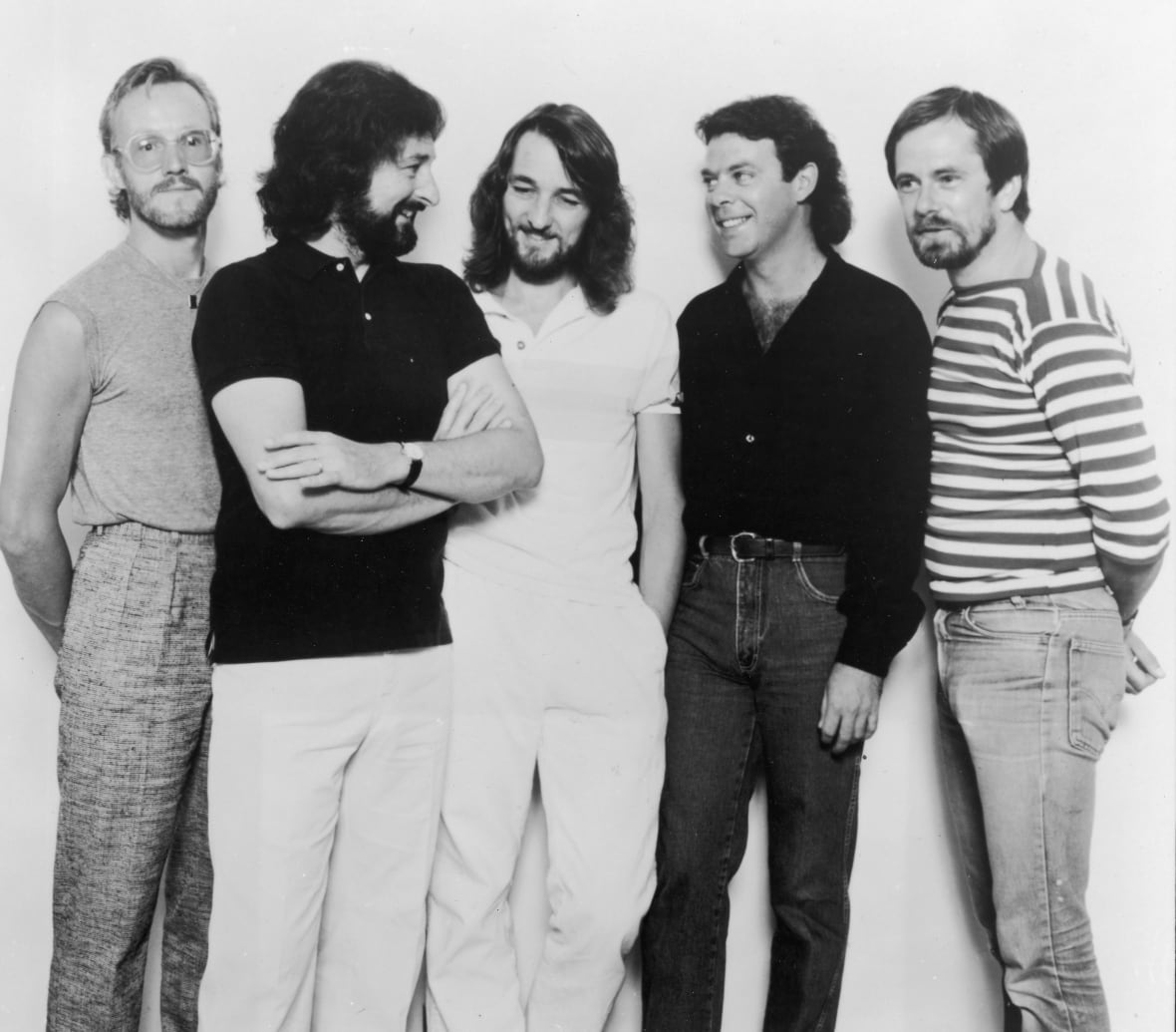 Five men are shown standing in a black and white photo from decades ago. Four of them have beards and one is clean shaven.