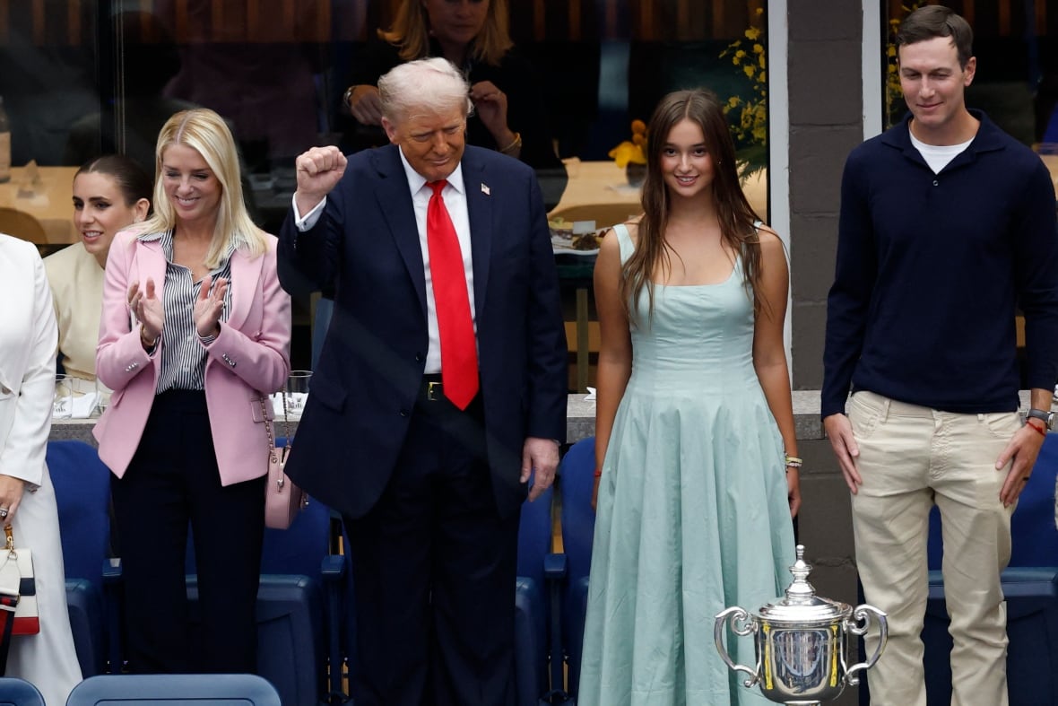Four people stand and applaud in a crowd