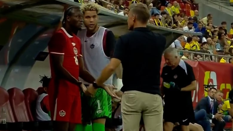 A soccer player and coach argue on the sidelines
