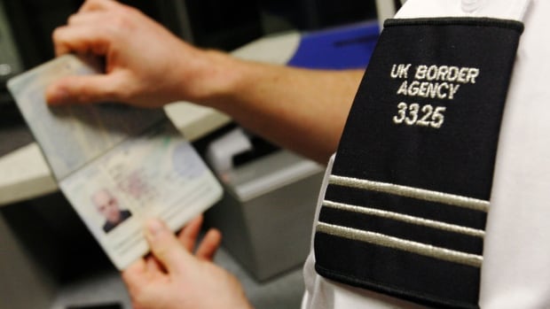 the shoulder patch of a uniform reading UK Border Agency and a man's hands holding a passport