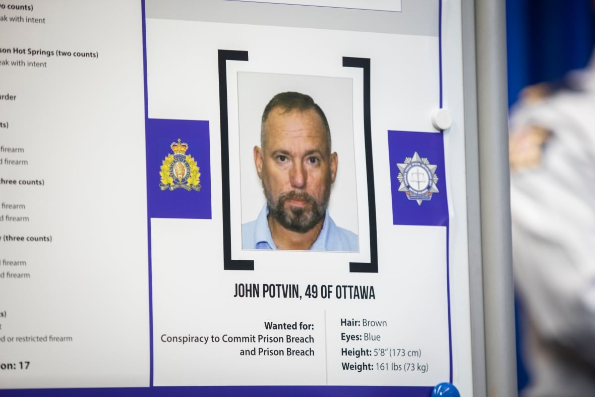 A mugshot of a white bearded man, with words underneath saying that he is wanted for conspiracy to commit prison breach and prison breach.
