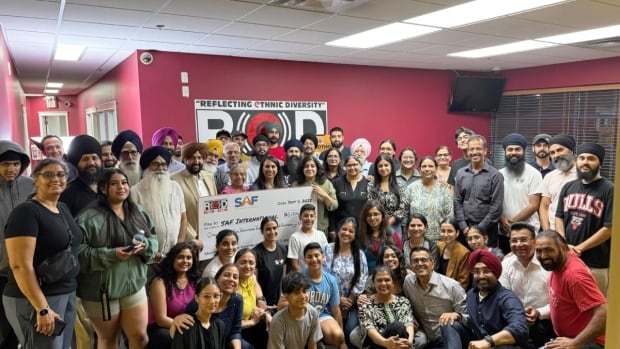 Crowd of 50ish people pose with a big cheque.