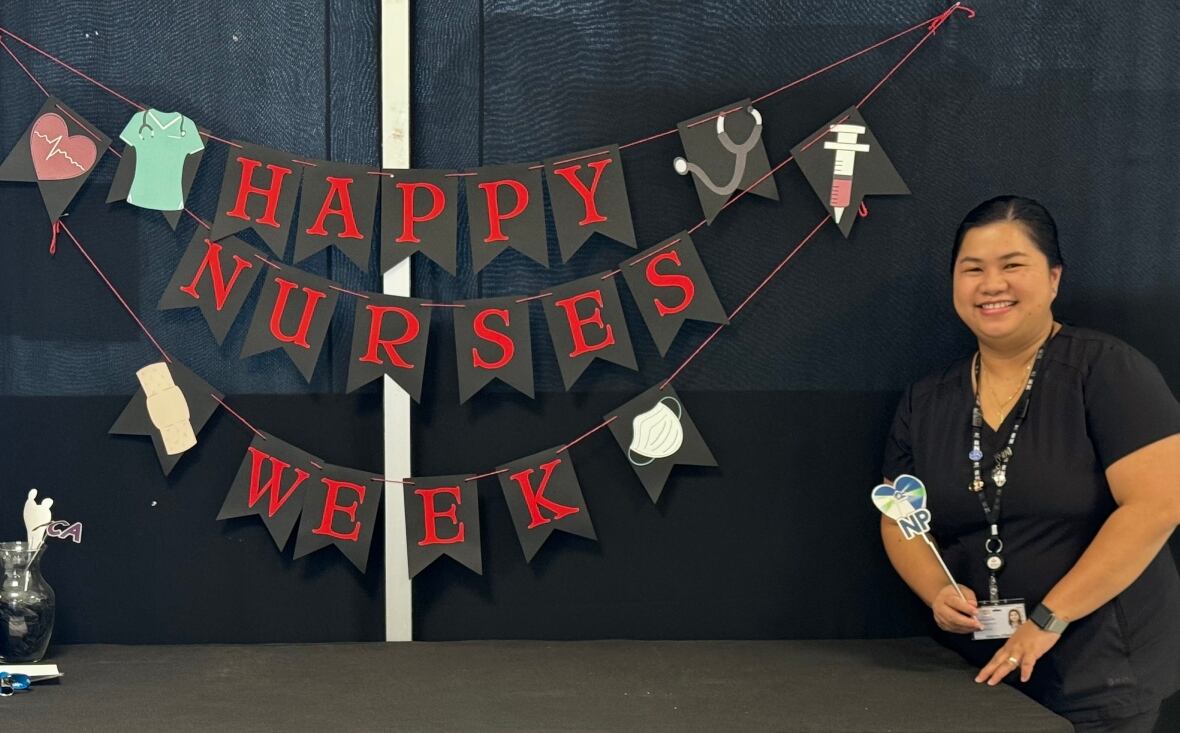 Nurse in scrubs standing next to sign that says happy nurses week. 