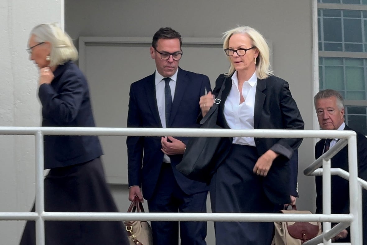 Four individuals in suits walk up a ramp into a building