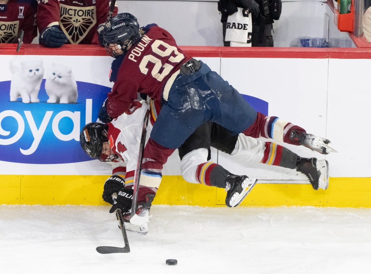 A hockey player hits another player along the boards.