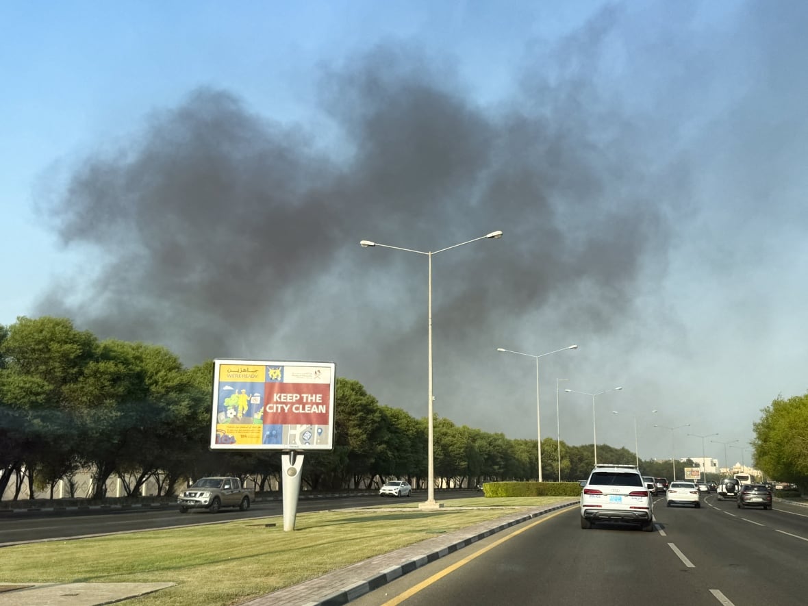 Carros em uma rodovia, com fumaça subindo acima deles em um dia claro.