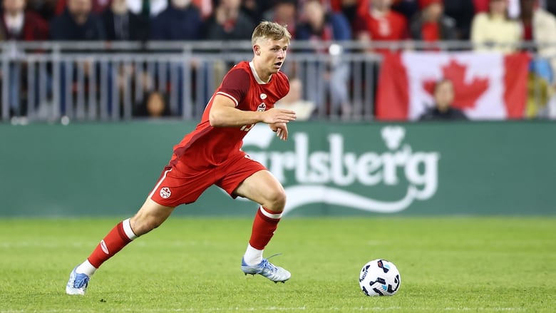 A soccer player runs with the ball.