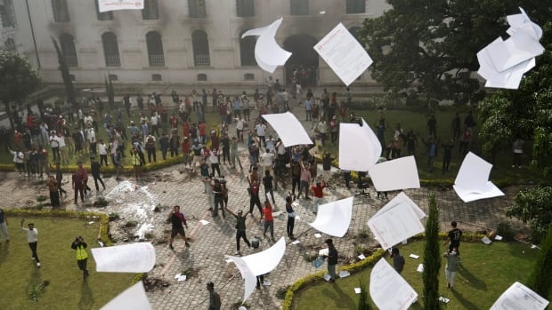 Paper rains down on a crowd of protesters, gathered in a large square.