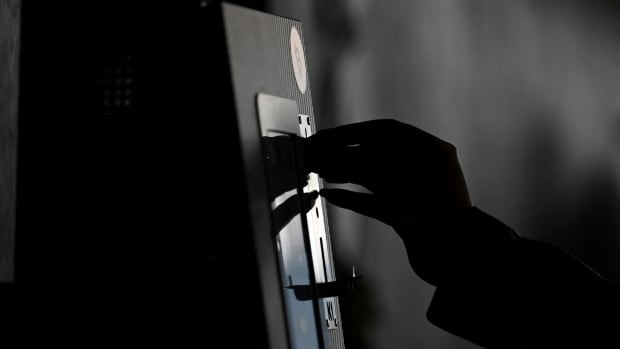 The silhouette of a hand touching a machine.