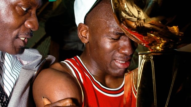 A man shows emotion while hugging a trophy.