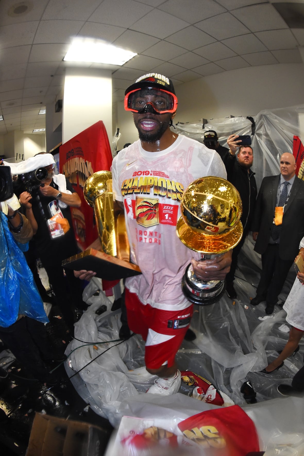 A man celebrates with two trophies in his hands.