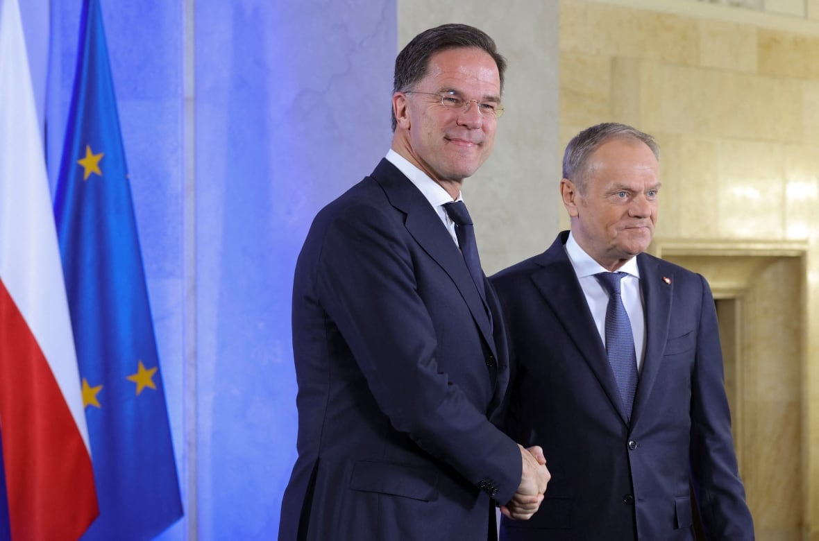 Two men shake hands during a photo op.