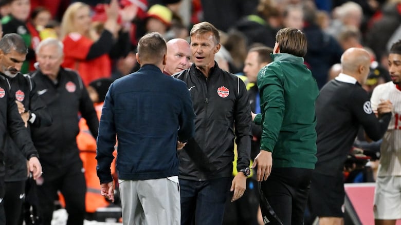 Two soccer coaches shake hands after a match.