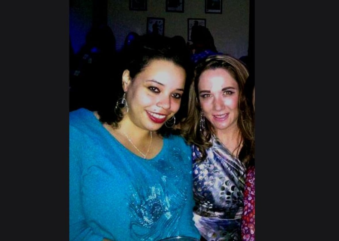 Two women pose for a photo, one in bright blue with dark hair on the left. A brunette stands to the right in a blue patterned shirt.