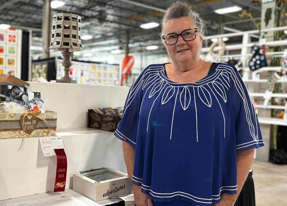 A woman stands next to a shelf of crafts