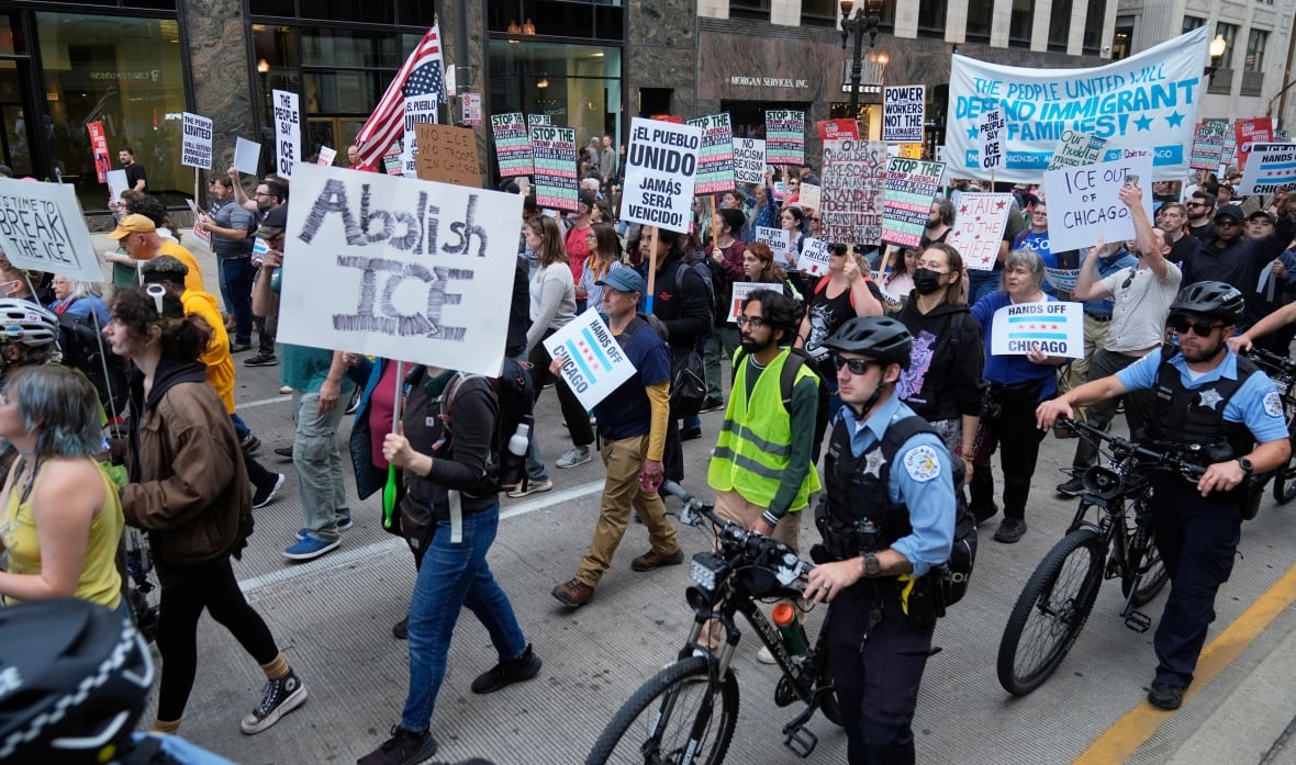 Demonstrators marching, including one carry a placard that says 'Abolish ICE'
