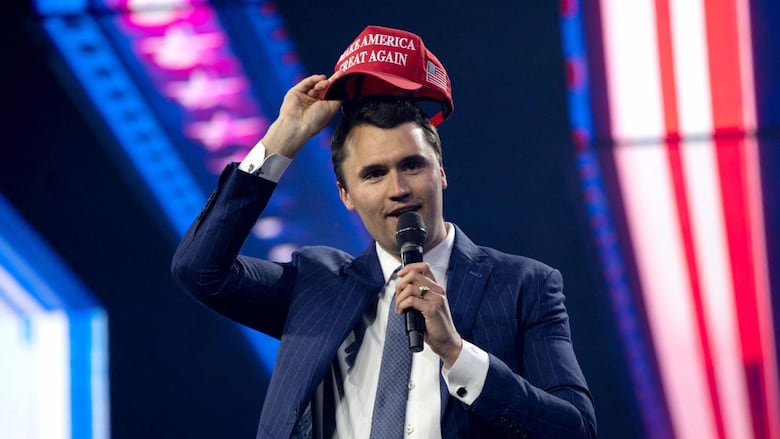 A man putting a 'MAGA' hat on his head.