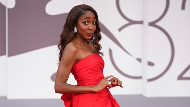 Ayo Edebiri poses for photographers on the red carpet for the film 'After the Hunt' during the 82nd edition of the Venice Film Festival in Venice, Italy, on Friday, Aug. 29, 2025. A woman in a red dress poses with her hands in front of her waist, her body positioned to the side from the camera's angle. She is pursing her lips in a cheeky expression, eyes wide.