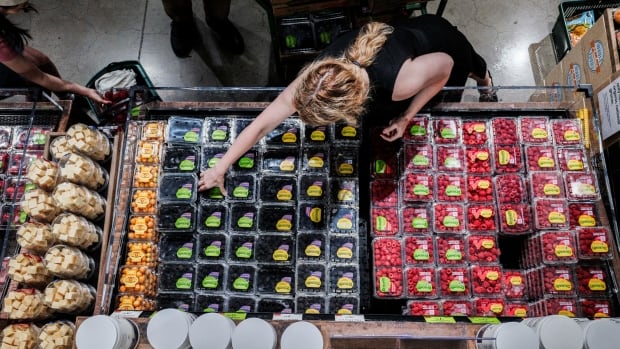 An overhead shot of a photo picking a container of berries in a grocery store.