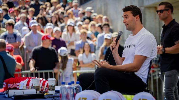A man speaks in front of a large crowd.