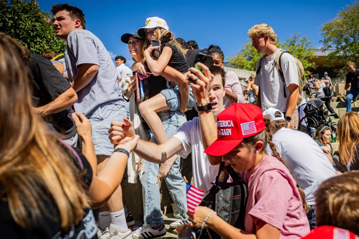 A crowd of young people looks out in shock.