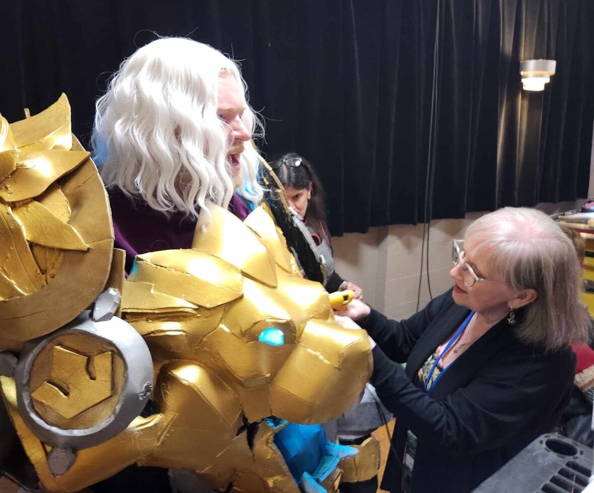 A woman uses a hot glue gun on a large cosplay costume