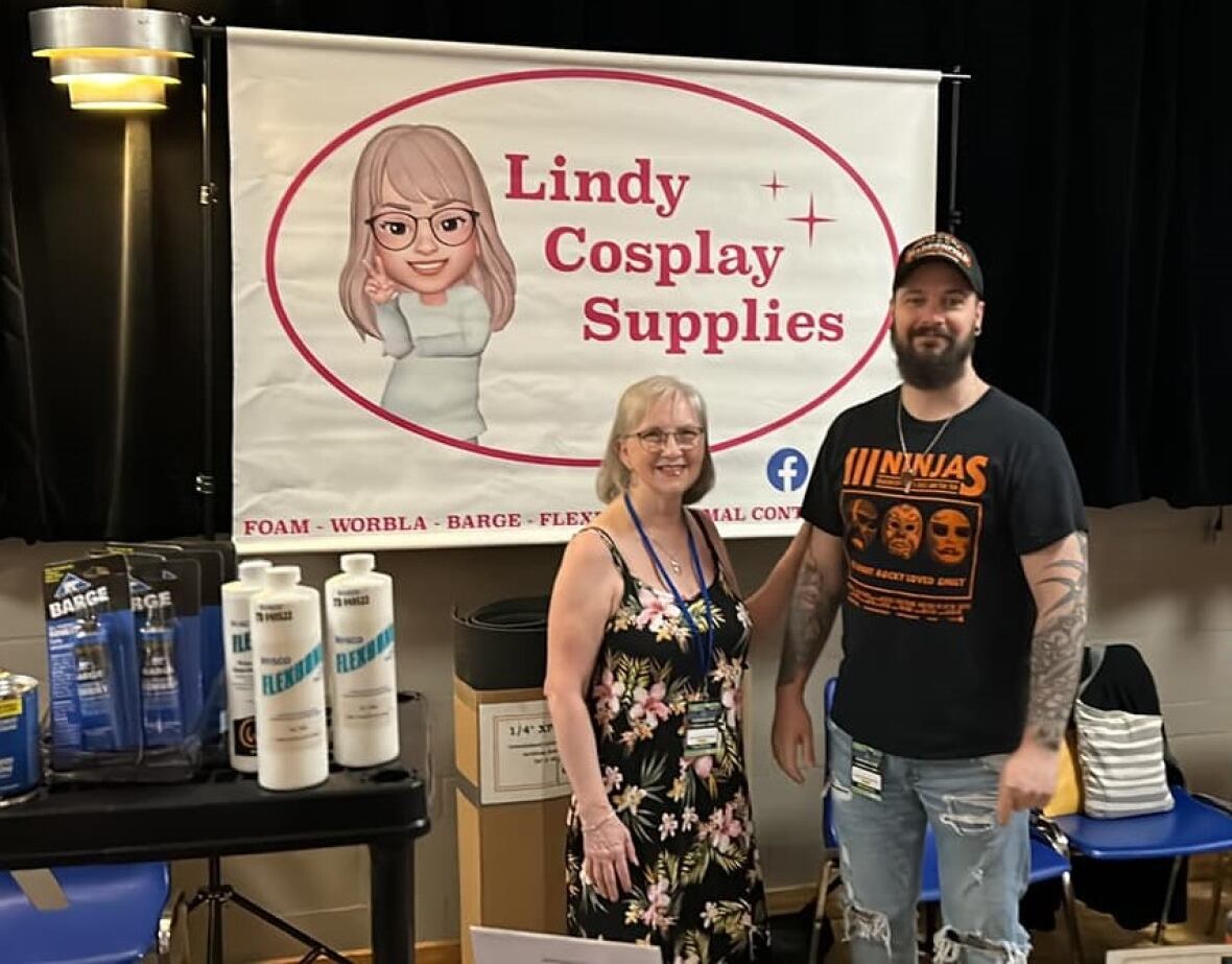 A mom and son stand in front of a sign that says "Lindy Cosplay Supplies"