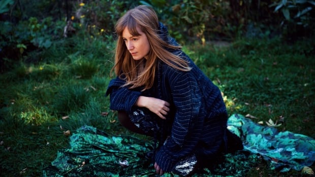 Tamara Lindeman, a white woman with long, blond hair, crouches in the grass on a green blanket.