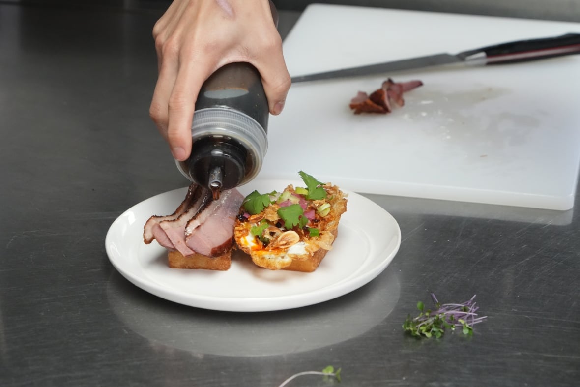 Duck pastrami getting sauced on a restaurant kitchen counter