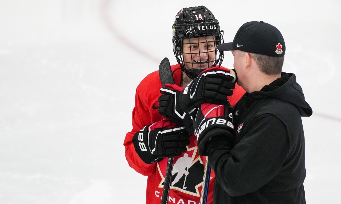 A hockey player and a coach chat on the ice.